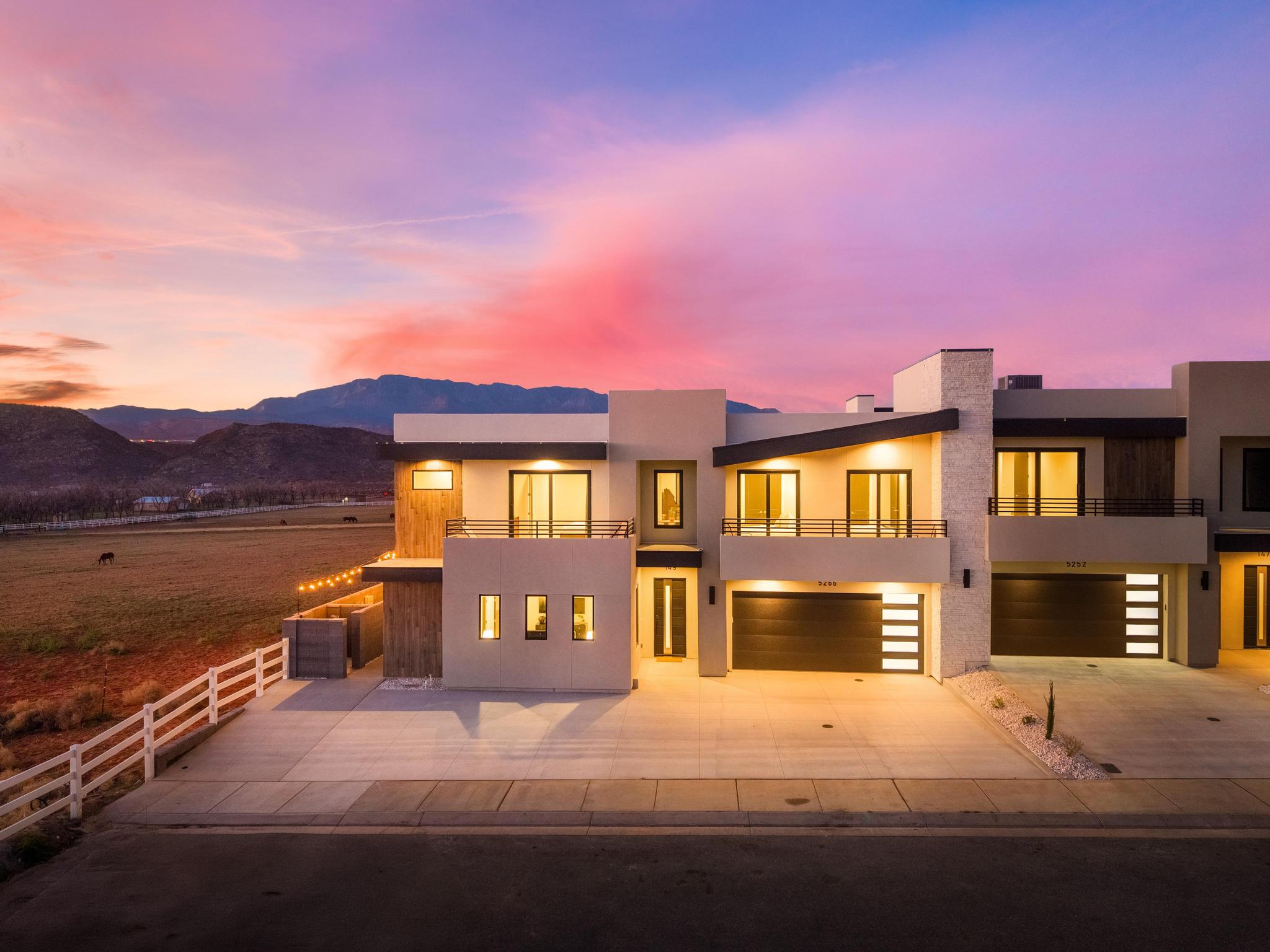 Modern home featuring a balcony, an attached garage, driveway, and stucco siding