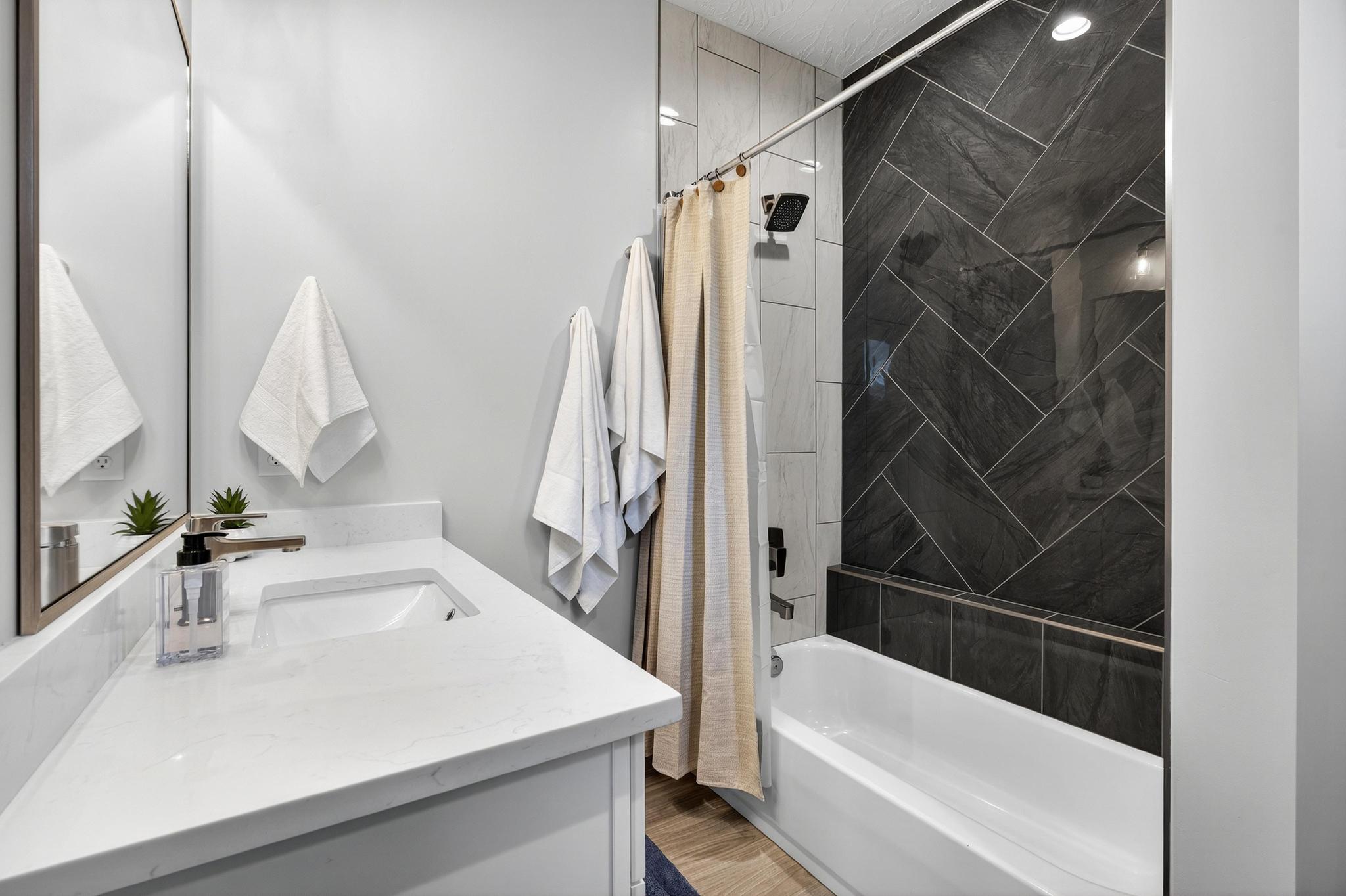 Full bath with shower / bath combination with curtain, vanity, and light wood-style floors