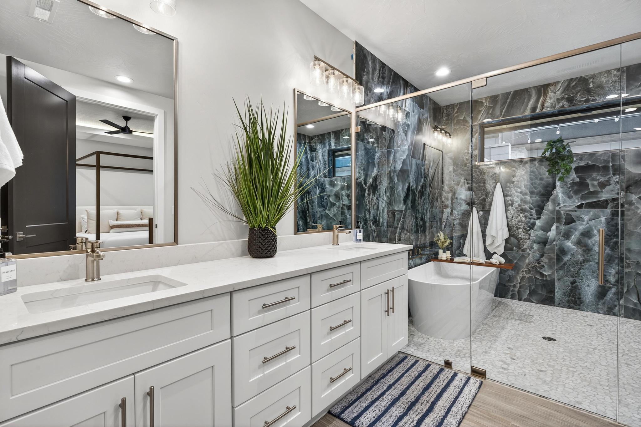 Ensuite bathroom with double vanity, a marble finish shower, a freestanding tub, tile walls, and a ceiling fan