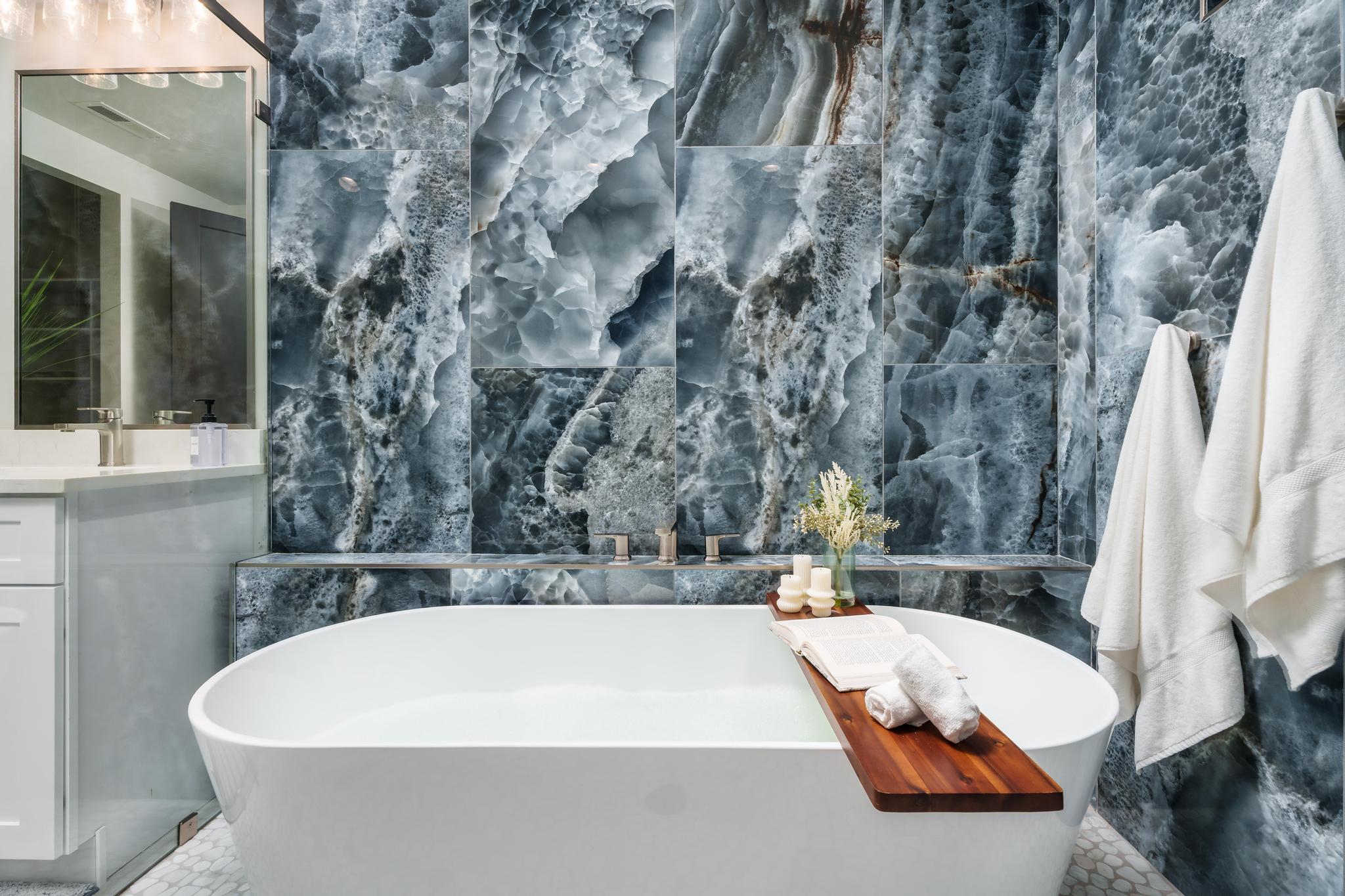 Bathroom with a soaking tub, vanity, and tile walls