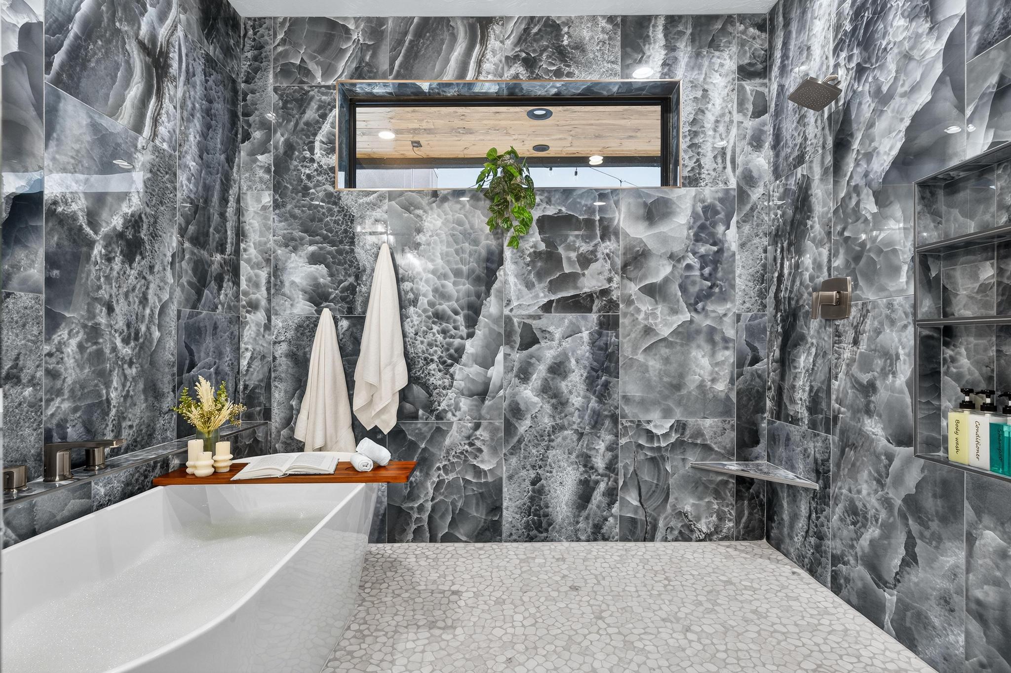 Full bathroom featuring a marble finish shower, a freestanding bath, and tile walls