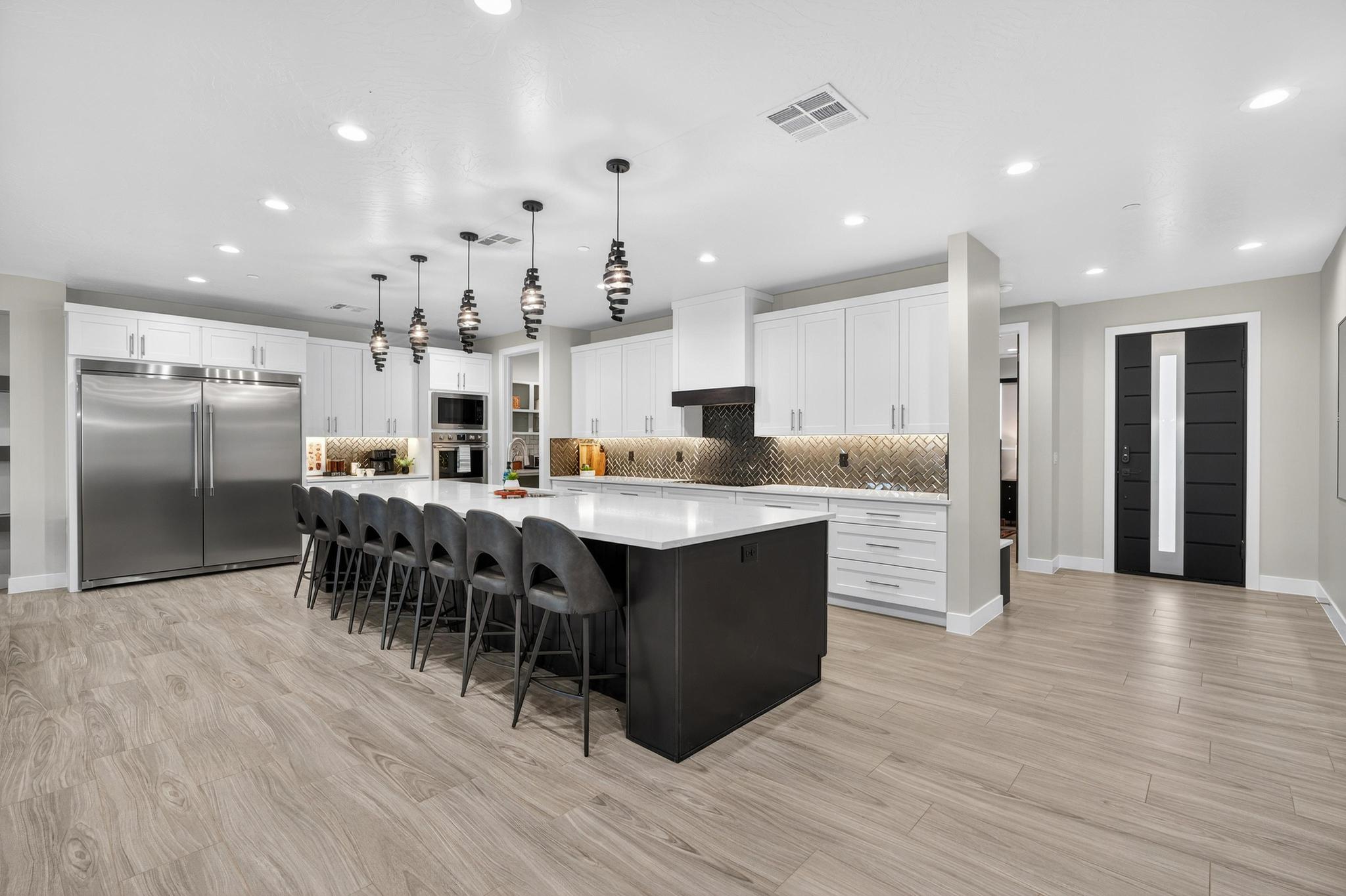 Dual tone kitchen featuring built in appliances, a kitchen bar, tasteful backsplash, light wood-style flooring, and two tone cabinetry