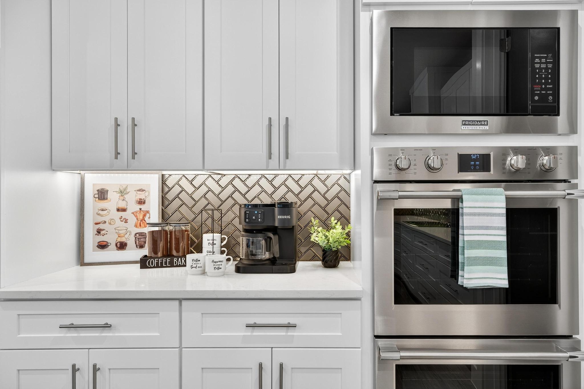 Kitchen with stainless steel appliances, light stone counters, white cabinetry, and tasteful backsplash