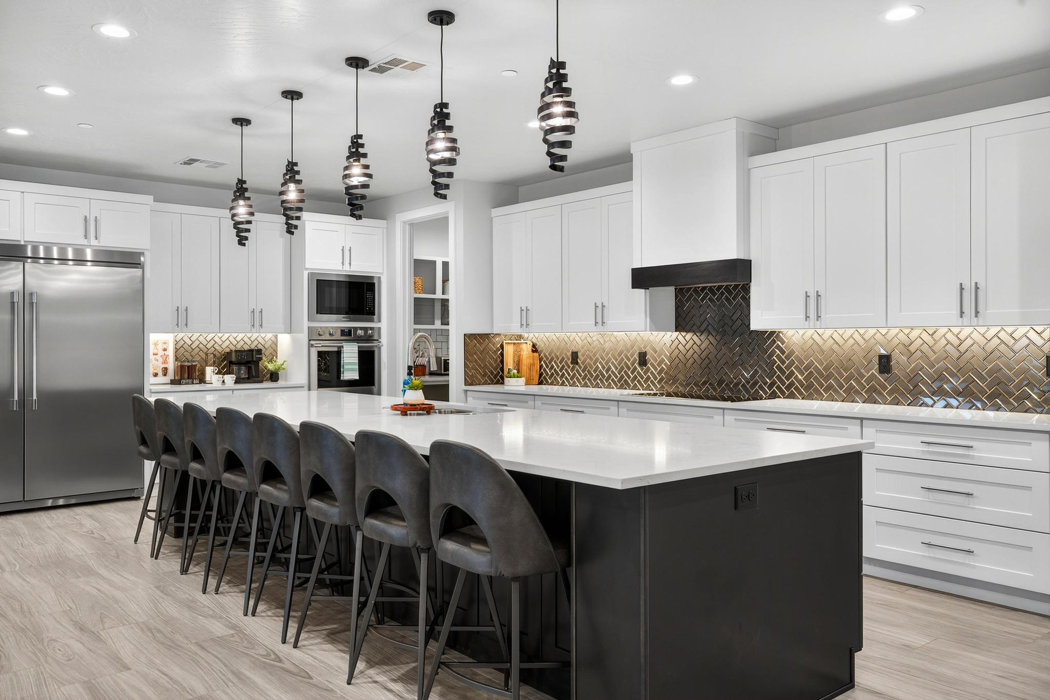 Two tone kitchen with a kitchen breakfast bar, built in appliances, a large island, tasteful backsplash, and two tone cabinetry