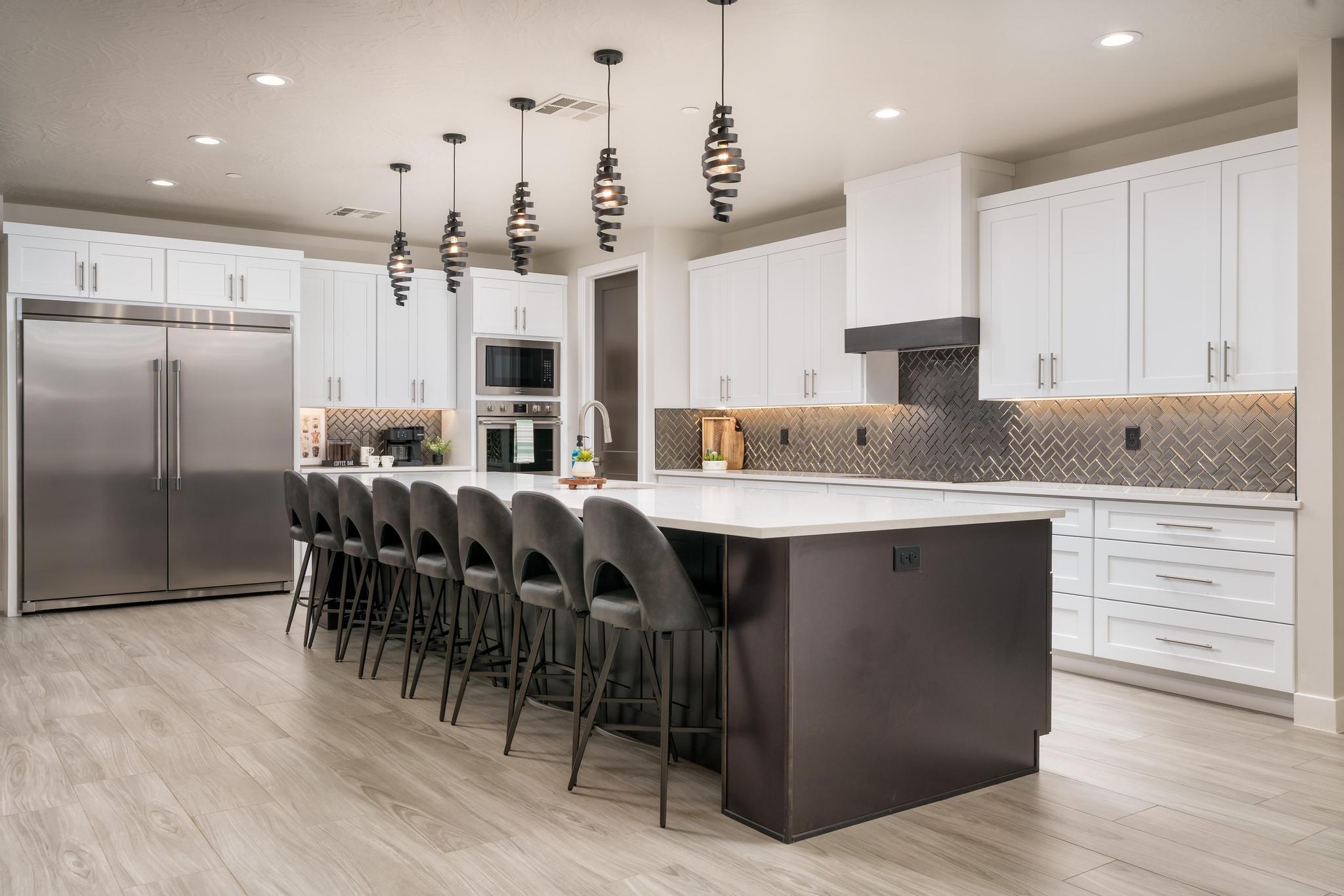 Dual tone kitchen with a breakfast bar, built in appliances, a large island, light wood-style flooring, and two tone cabinetry