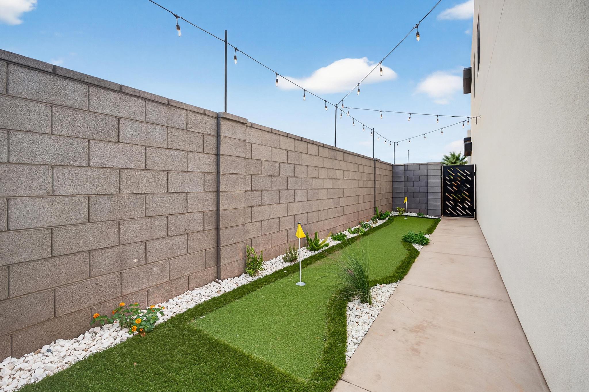 Fenced yard featuring a putting green and a gate