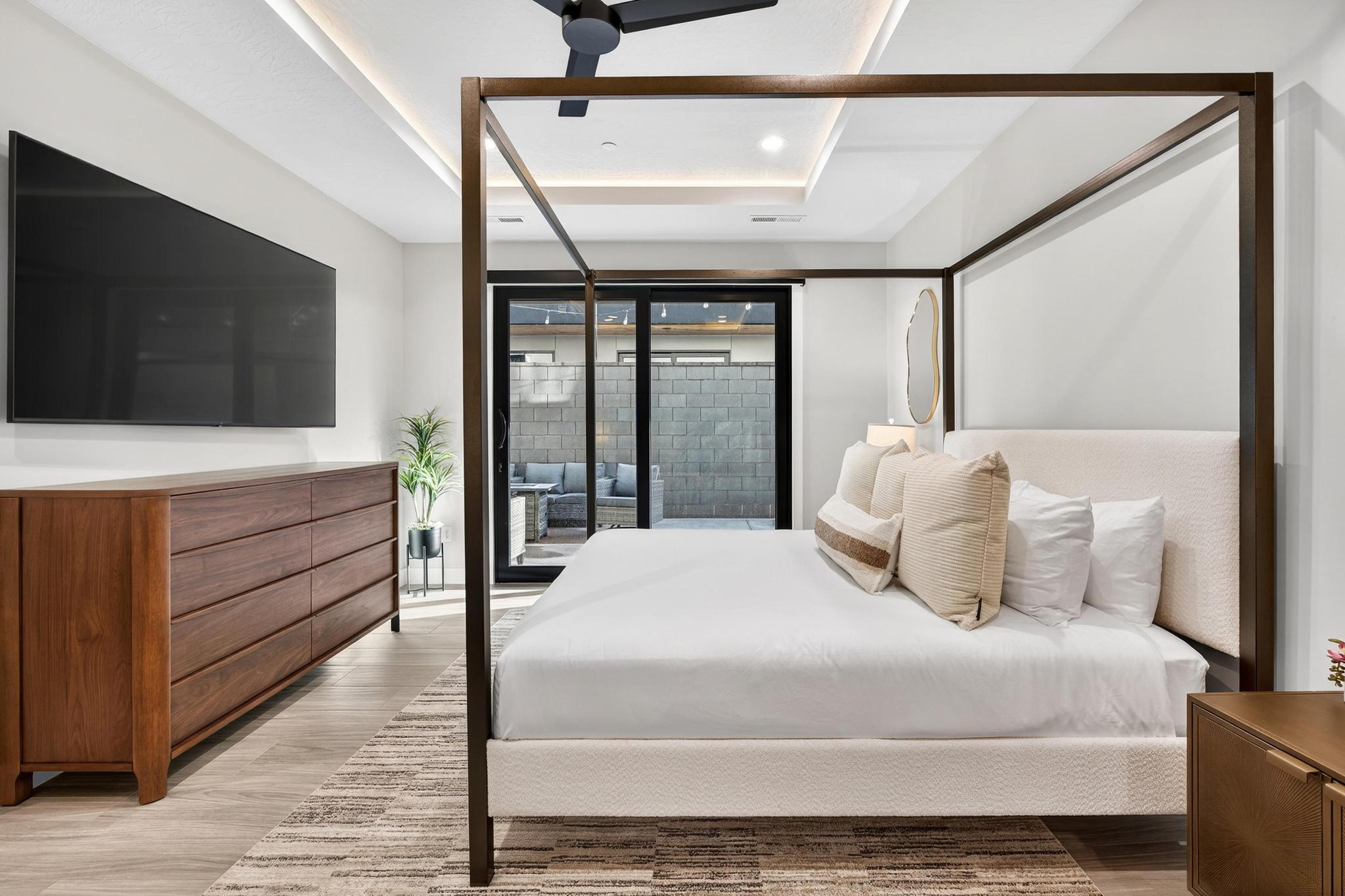 Bedroom with light wood-style flooring, ceiling fan, and a tray ceiling