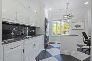 Second Laundry area featuring stacked washer / drying area, crown molding, and suspended lighting, built in cabinetry and desk