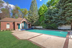 Swimming pool featuring expansive patio area and a pool house.