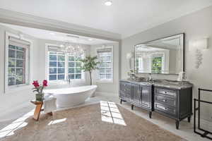 Primary ensuite bathroom. Inspired by the finest spa like quality, with heated floors, dual vanities, crown molding, tile floors, a marble finish shower, and a soaking tub surrounded by charming paned windows.
