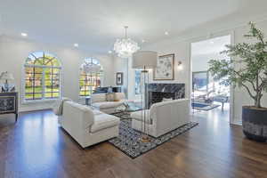 Living room featuring  gleaming wood flooring, ornamental molding, fireplace and so much natural light.