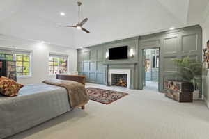 Expansive primary bedroom with ornamental decorative molding, a fireplace with flush hearth, light colored upscale carpet, and recessed lighting,