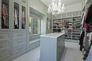 Exclusive boutique inspired primary Walk in closet featuring custom builtins, chandelier and natural light