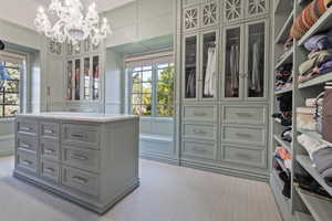 Exclusive boutique inspired primary Walk in closet featuring custom builtins, chandelier and natural light