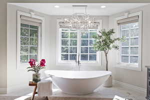 Charming soaking tub with natural light, elegant chandelier, overlooking a very private and secluded backyard.