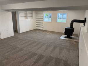 Basement featuring dark carpet and a wood stove