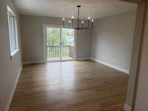 Unfurnished dining area with suspended lighting and light wood-type flooring
