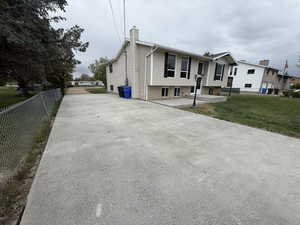 View of home's exterior with a chimney, brick siding, driveway, and a patio