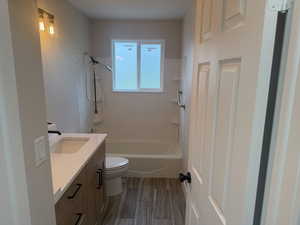 Full bathroom with vanity, dark wood-style flooring, and washtub / shower combination