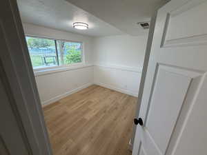 Empty room featuring a textured ceiling and light wood-style floors