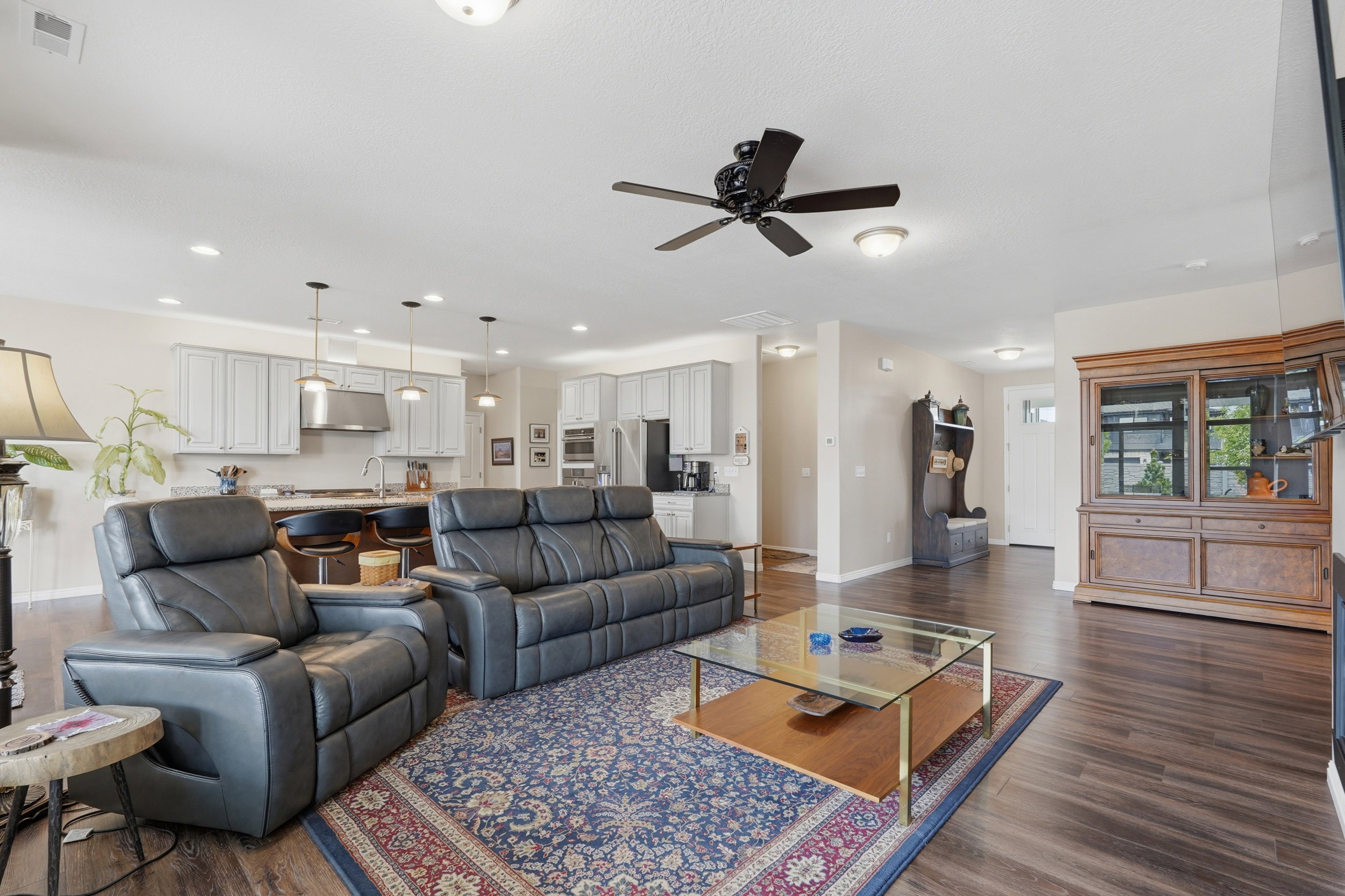 Living room with ceiling fan, dark wood-style flooring, and recessed lighting