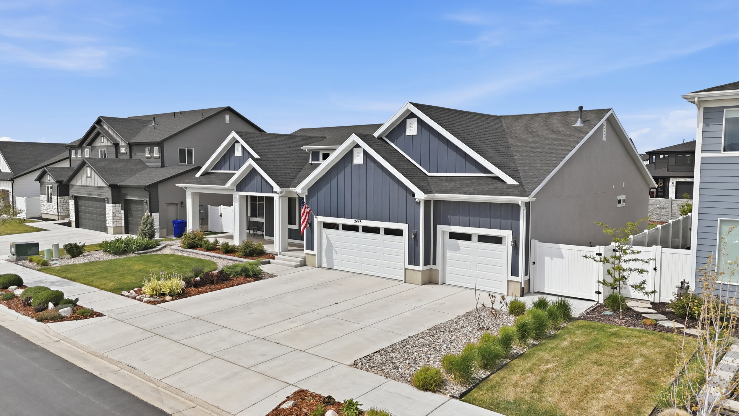 View of front facade featuring board and batten siding, a gate, concrete driveway, roof with shingles, and an attached garage