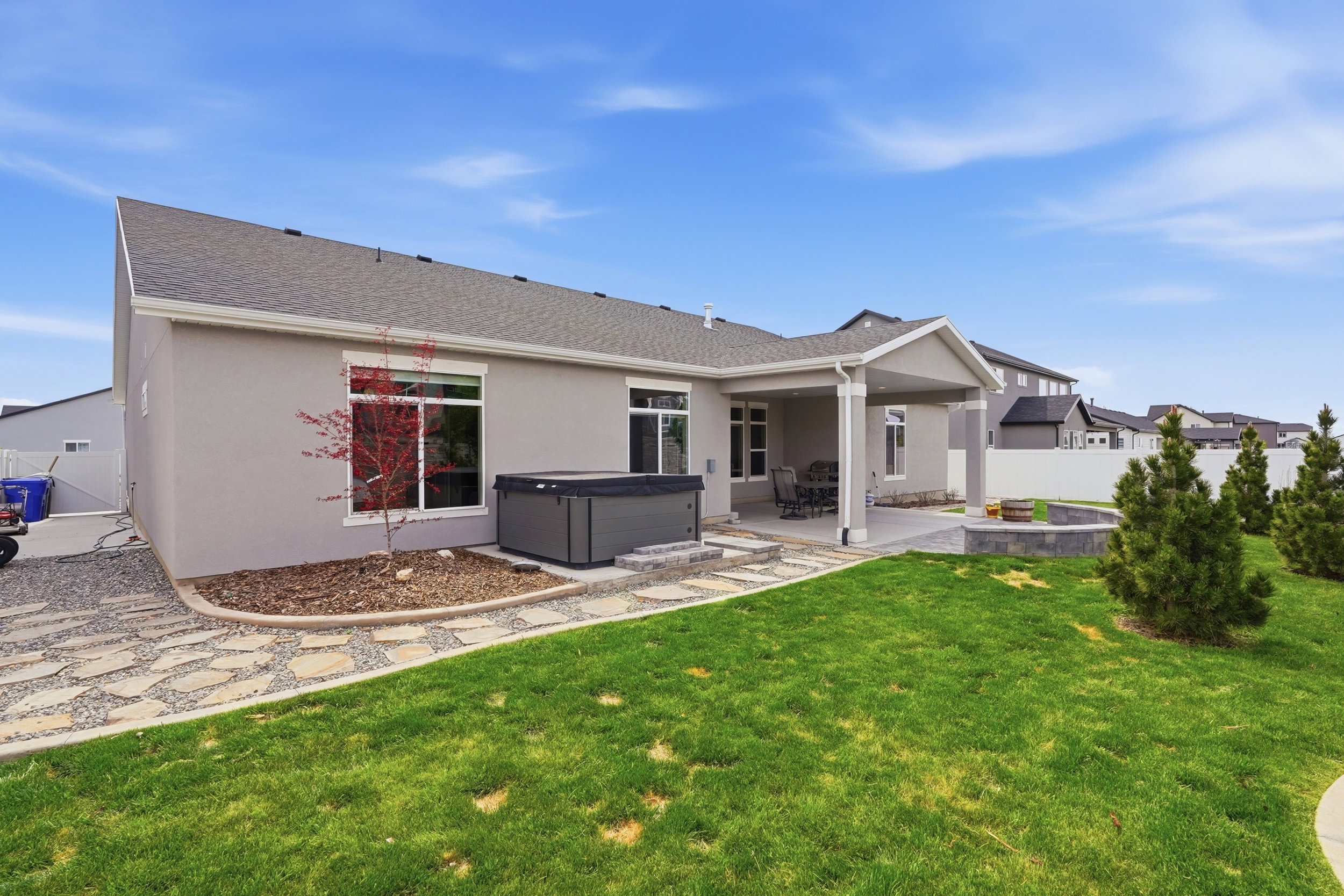 Back of house featuring a hot tub, a fenced backyard, stucco siding, a patio area, and a shingled roof