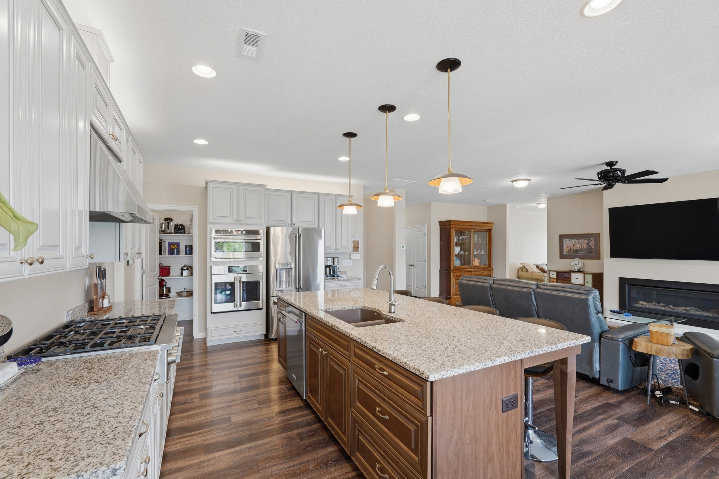 Two tone kitchen featuring light stone countertops, a breakfast bar area, open floor plan, two tone cabinetry, and an island with sink