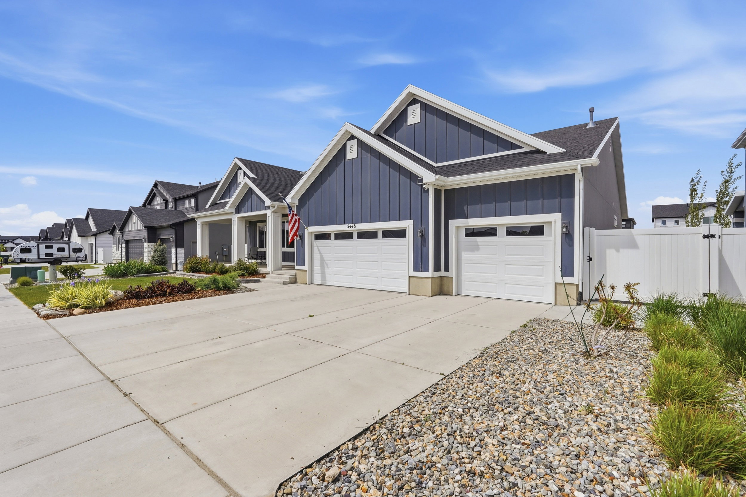 View of front of house with board and batten siding, an attached garage, driveway, roof with shingles, and a residential view