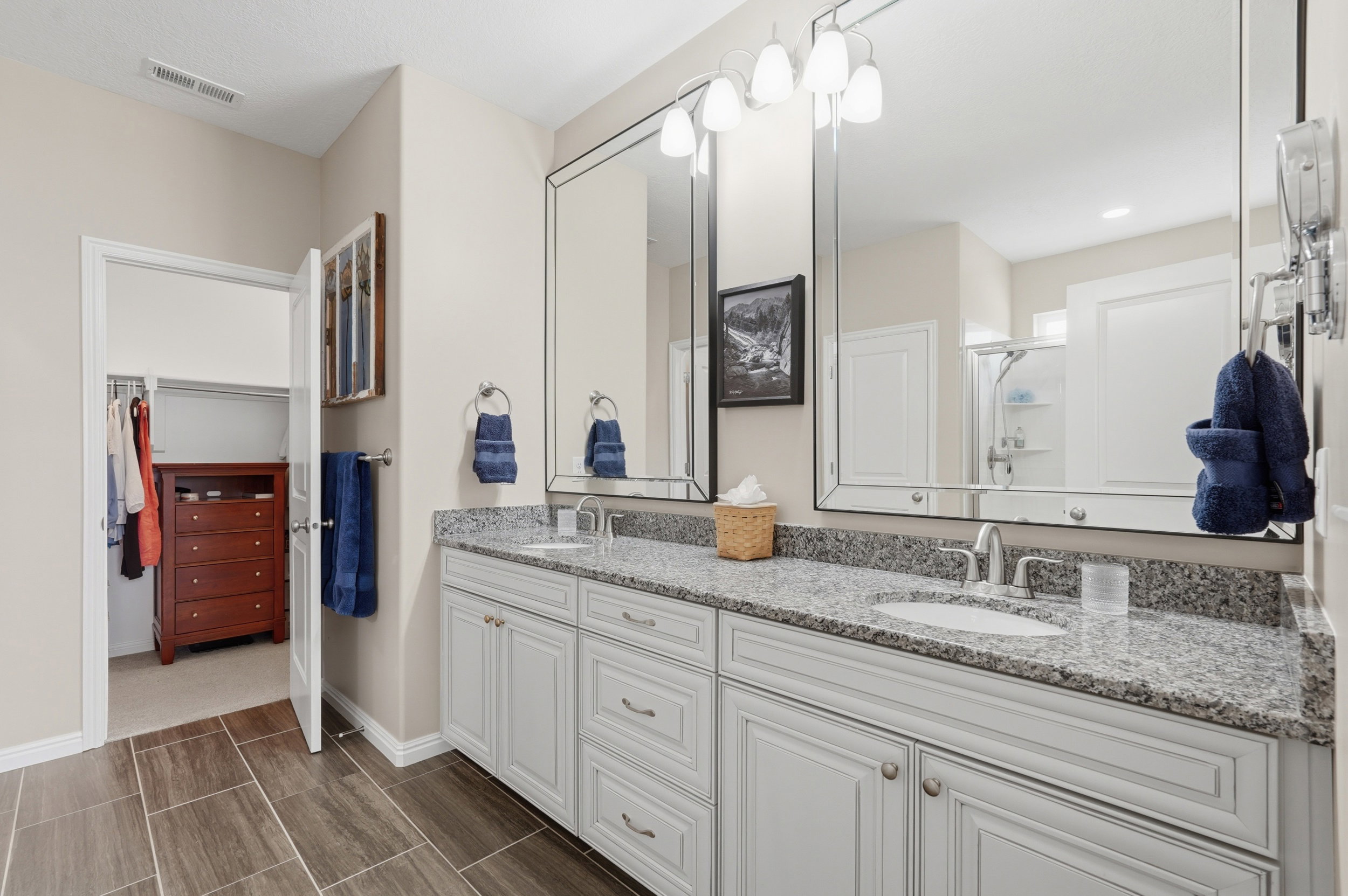 Full bath featuring double vanity, a stall shower, and a walk in closet