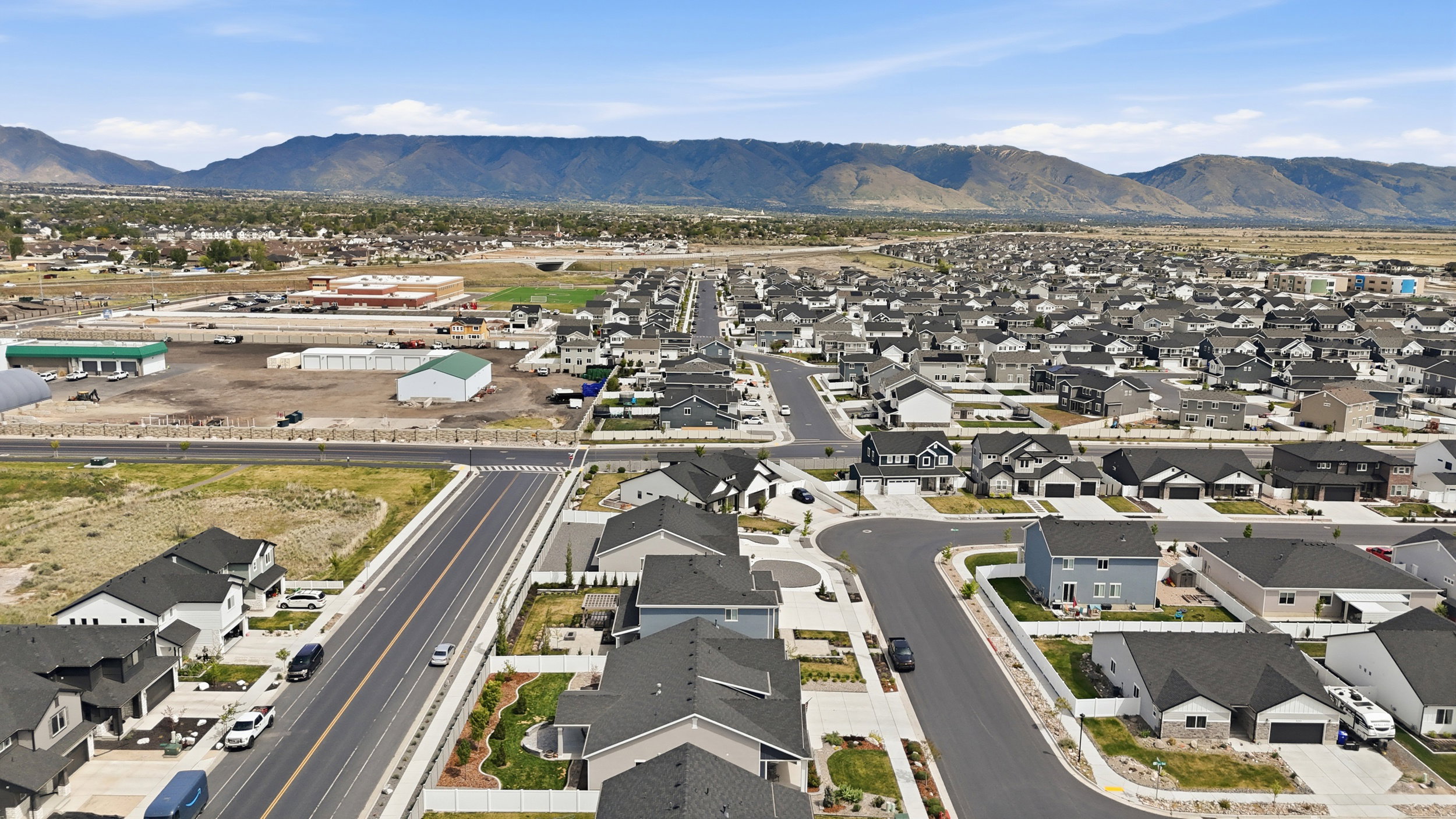 Aerial view of property and surrounding area featuring nearby suburban area and a mountain backdrop