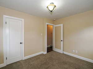 Unfurnished bedroom featuring dark carpet and a textured ceiling