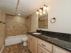 Bathroom featuring vanity, shower / bath combination, and a textured ceiling