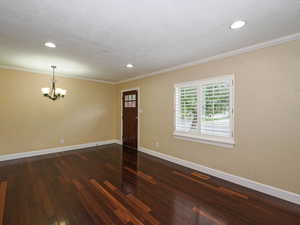 Entryway featuring dark wood-type flooring, suspended lighting, and ornamental molding