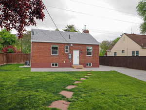 Rear view of house with roof with shingles, brick siding, a chimney, and a patio