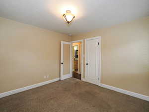 Empty room with baseboards and dark colored carpet