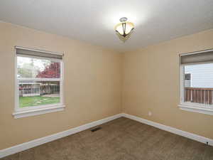 Spare room with dark colored carpet and a textured ceiling