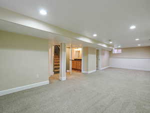 Finished basement with recessed lighting and light carpet