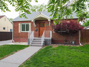 View of front of house featuring roof with shingles and brick siding
