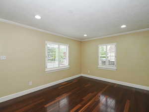 Spare room with dark wood-style flooring, recessed lighting, and ornamental molding