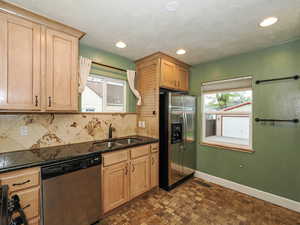 Kitchen featuring stainless steel appliances, decorative backsplash, dark stone countertops, and recessed lighting