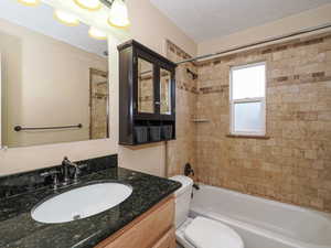 Full bathroom with vanity, shower / bath combination, and a textured ceiling