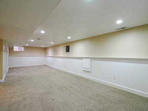 Finished below grade area with a wainscoted wall, carpet floors, and recessed lighting