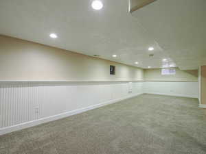 Below grade area featuring a wainscoted wall, recessed lighting, and carpet floors
