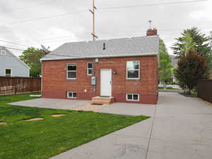 Rear view of house with roof with shingles, brick siding, and a chimney