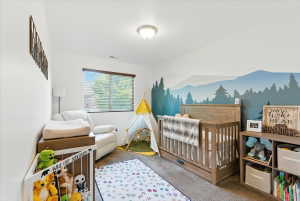 Bedroom with a crib and carpet floors