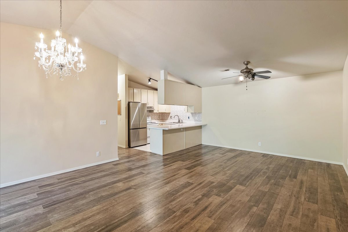 Kitchen featuring open floor plan, lofted ceiling, freestanding refrigerator, a peninsula, and decorative backsplash