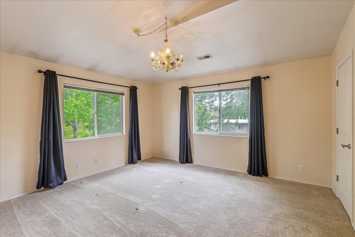 Unfurnished room featuring hanging lights and light carpet