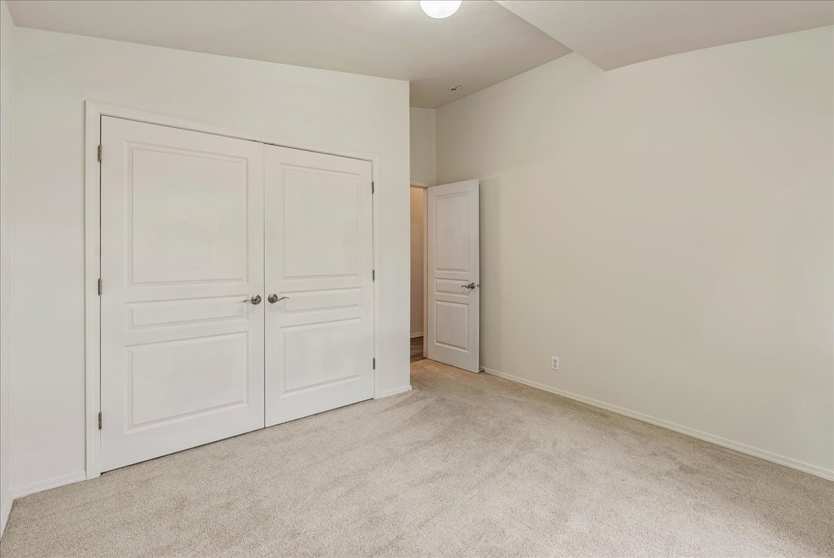 Unfurnished bedroom with light colored carpet and a closet