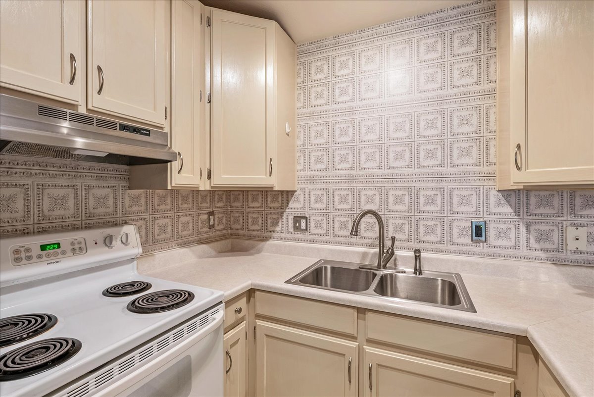 Kitchen featuring white range with electric cooktop, light countertops, and cream cabinetry